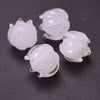 Several clear glass charm pendants shaped like lily of the valley blooms are displayed on a dark surface.