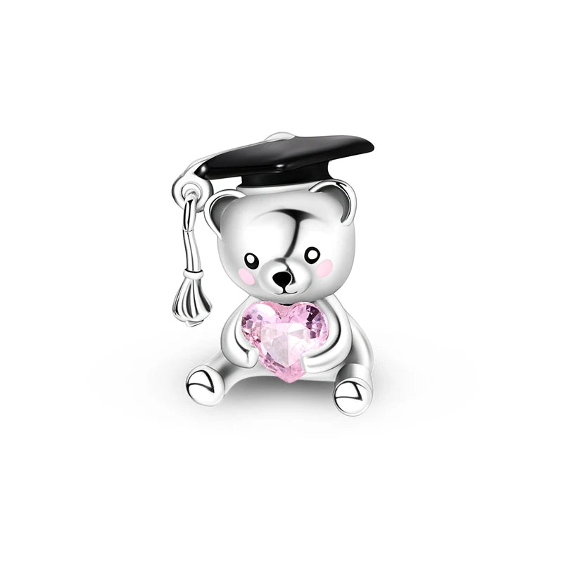 A silver charm bead shaped like a bear with a graduation cap and a pink heart gemstone.