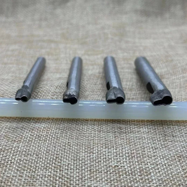 A set of five precision leather hole punches with metal tips resting on a white plastic rod.
