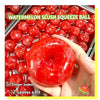 A hand holds a red watermelon slush squeeze ball next to a tray of similar red balls.