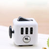A white fidget cube with a rotating joystick and magnetic buttons resting on a white surface.