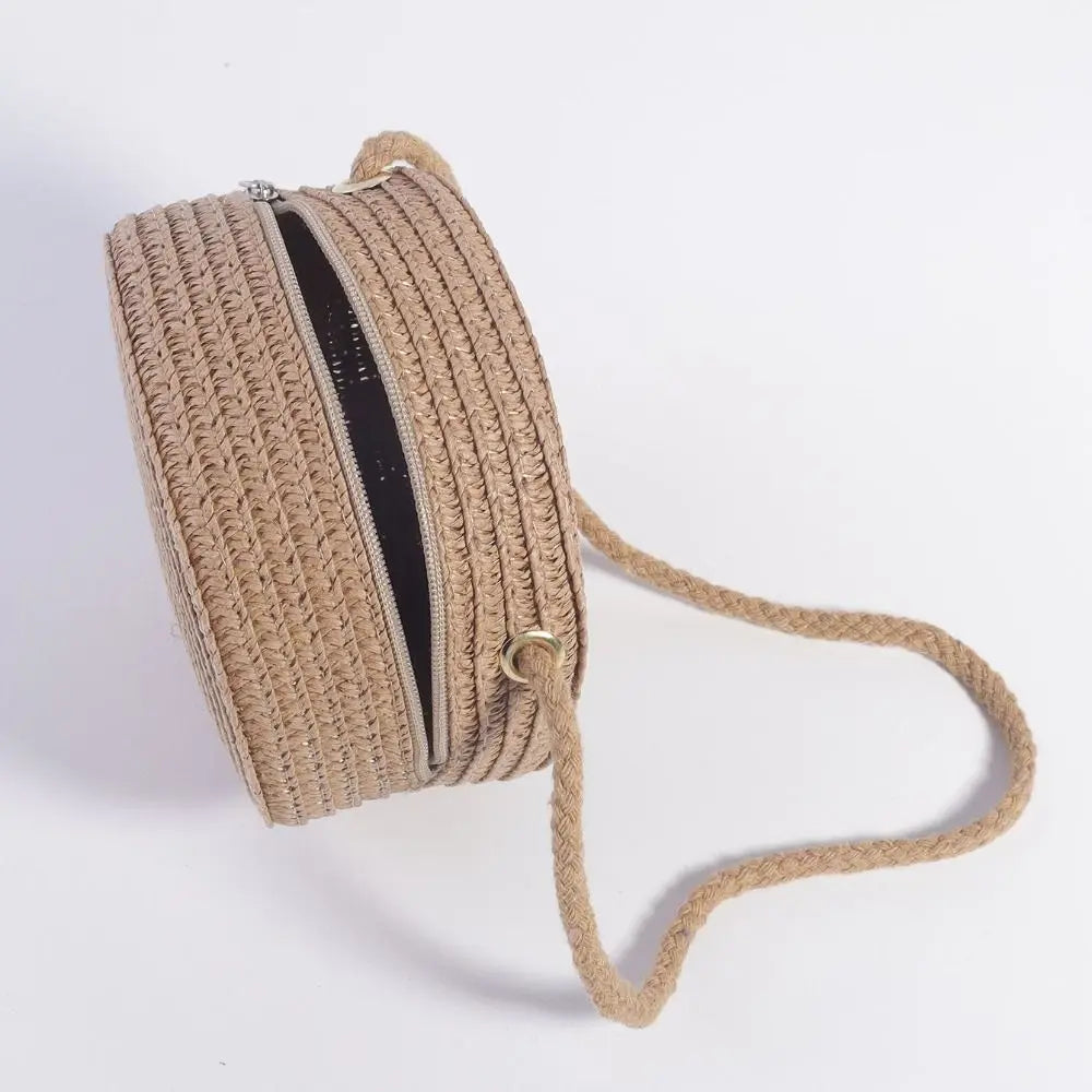 Handwoven straw crossbody bag with a lace bow, shown rolled up and with a long strap.