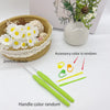 A set of crochet tools including a hook, stitch markers, and needles are displayed next to a potted plant.