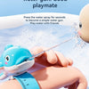 A hand is squeezing a water gun shaped like a turtle or dolphin to spray water, with a summer theme background.