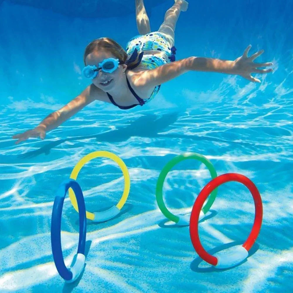 A smiling girl is jumping in clear blue water with a set of colorful pool diving rings.