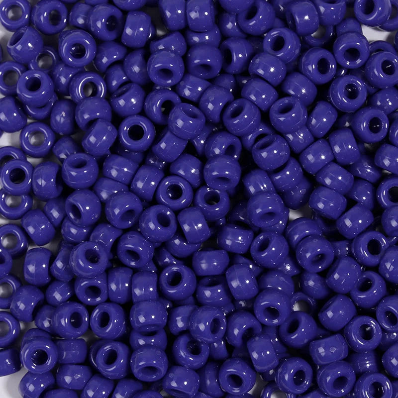 A close-up view of a pack of small, round, purple pony beads for jewelry making and craft projects.