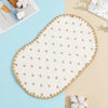 A light beige flat pillow with a white background and scattered pink hearts, resting on a light blue surface.