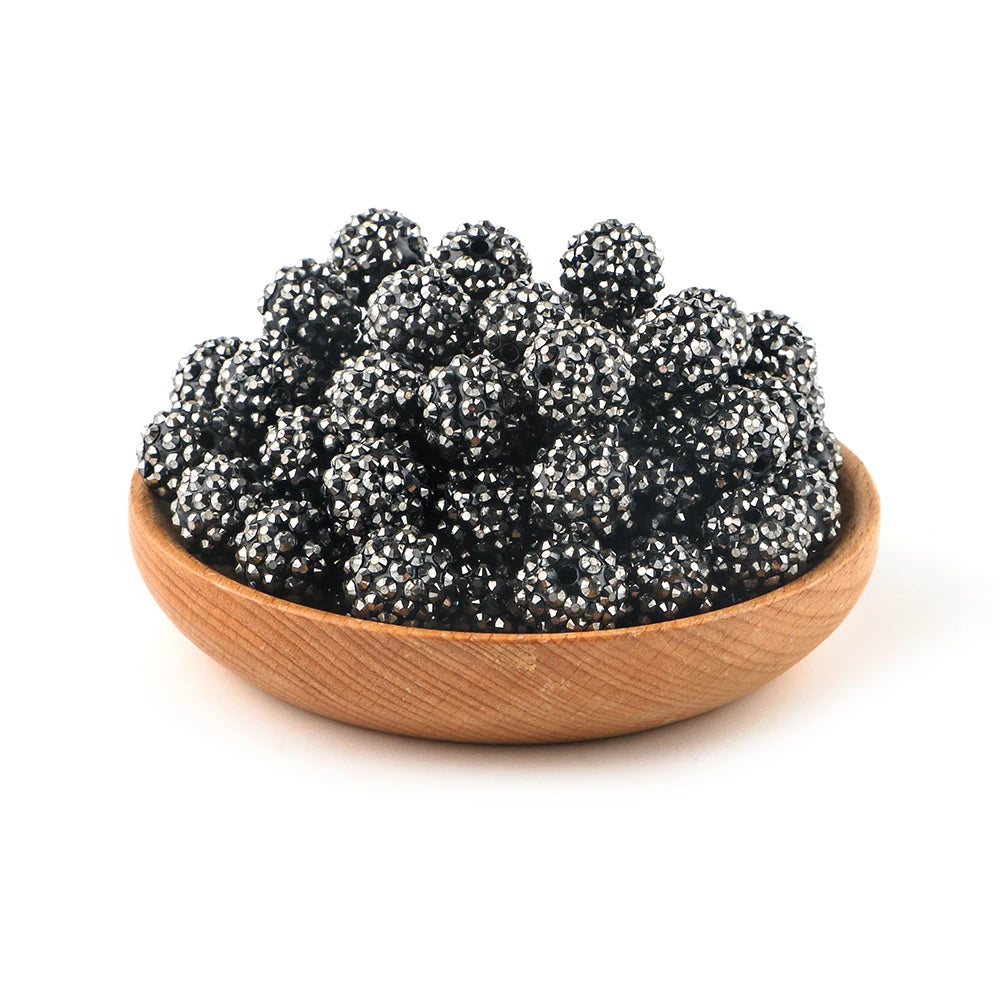 A wooden bowl filled with dark, glittering rhinestone resin bayberry ball beads for jewelry making