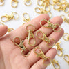 A hand holds several gold-colored metal swivel snap hooks with key rings.