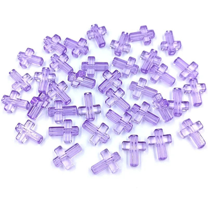 A pile of small, translucent purple acrylic cross beads for jewelry making