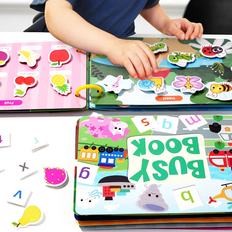 A toddler is interacting with an interactive learning book featuring insects and colorful stickers.