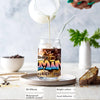 A glass of liquid being poured into a glass jar featuring zodiac sign graffiti art stickers.