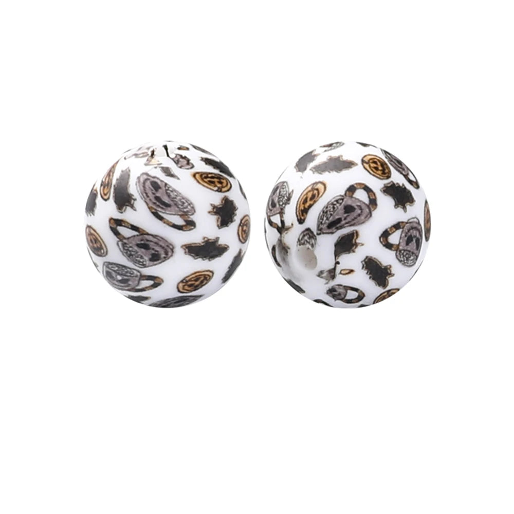 Two round silicone beads with a black and gold leaf pattern for jewelry making