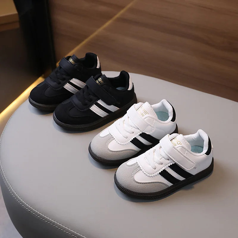 A pair of black and white casual sneakers are displayed on a light surface.