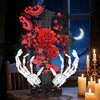 A dark gothic skeleton hand and rose cross building set displayed on a wooden surface.