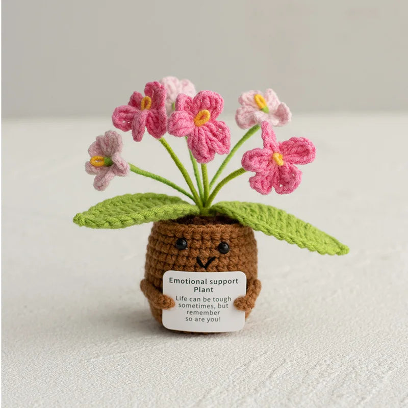 Handmade crochet plant with pink flowers growing from a brown pot