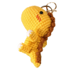 Handmade crochet yellow dinosaur keychain with brown texture and a gold ring.