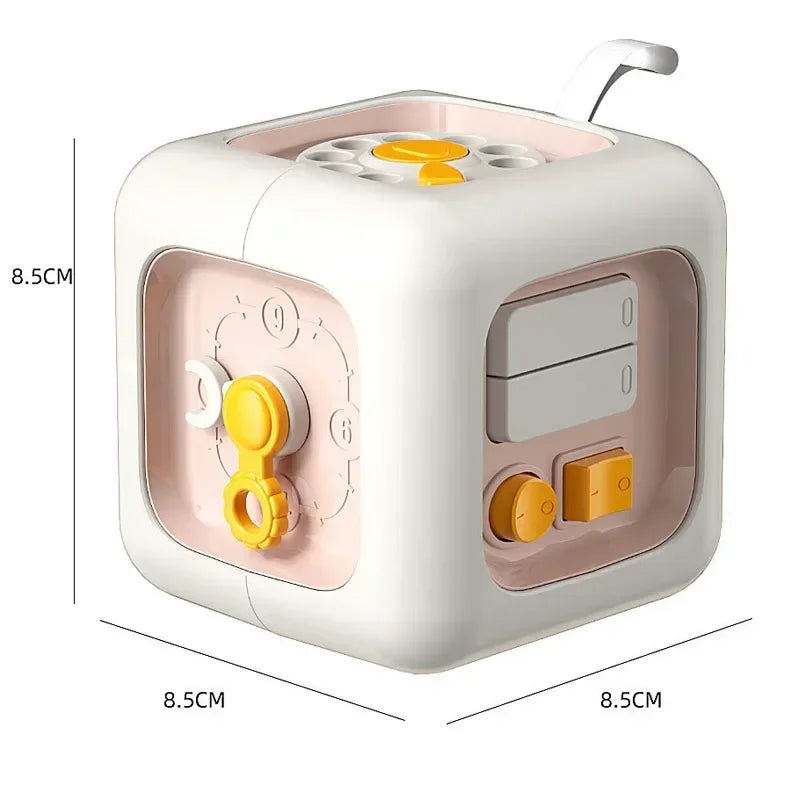 A white Montessori busy cube with a pink accent, featuring multiple manipulative components for toddlers.
