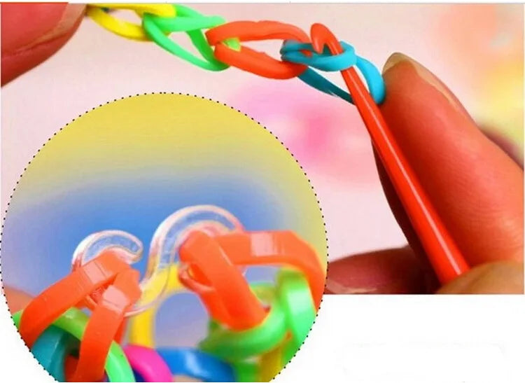 A hand is shown manipulating colorful glow-in-the-dark loom bands for a bracelet making kit.