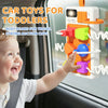 A toddler is interacting with an orange and yellow interactive busy board for travel featuring auction cups and lights.