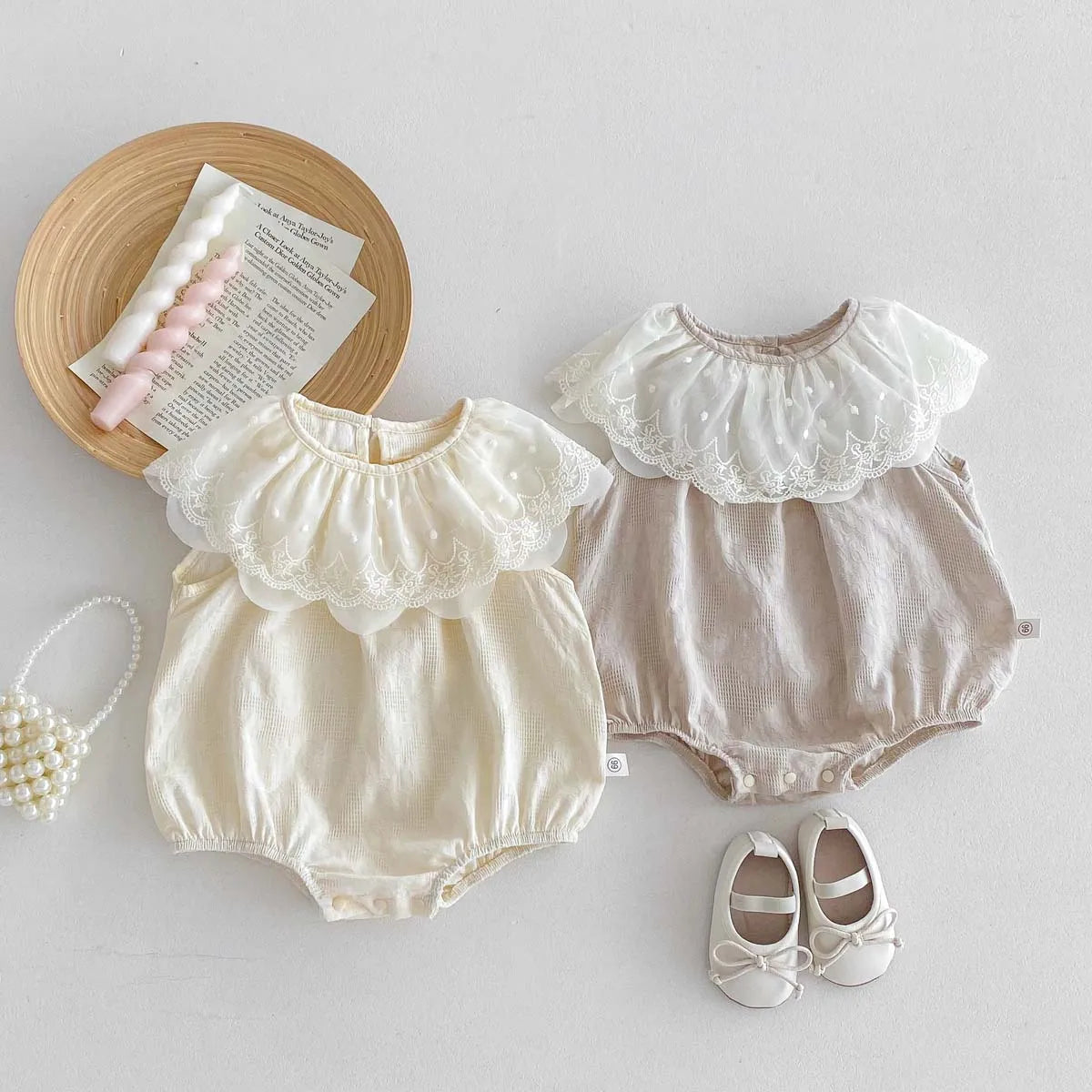 A beige baby girl sleeveless jumpsuit with a white lace collar and matching shoes, displayed on a light background.