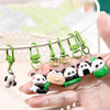 A hand holds several green panda-themed keychains with silver clasps and loops.