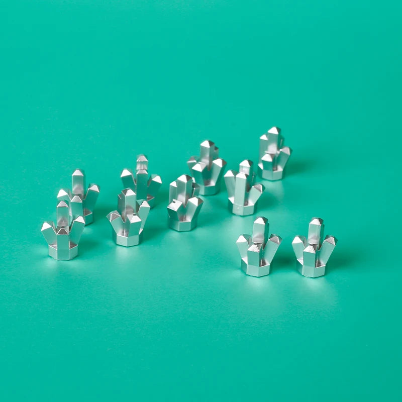 A collection of silver building block treasure chest pieces scattered on a teal surface.