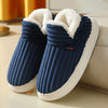 A pair of navy blue faux fur slippers with white soles resting on a light surface.