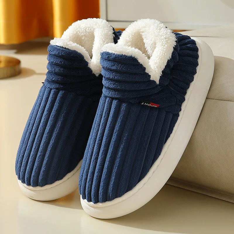 A pair of navy blue faux fur slippers with white soles resting on a light surface.