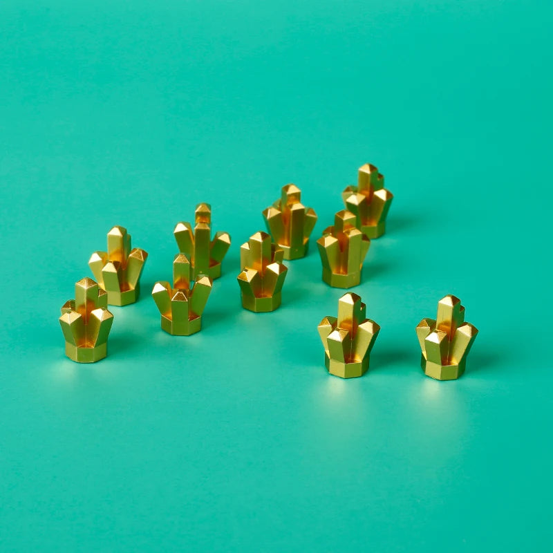 A collection of small, gold-colored building blocks shaped like treasure chests arranged on a teal surface.