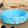 A blue inflatable kids play pool with cartoon fish and sea life resting on sand.
