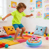 A young boy is playing with a unicorn hover soccer ball that lights up and plays music on the floor.