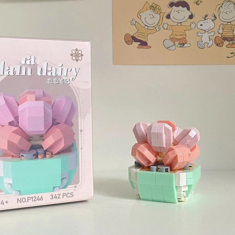 A pink and mint green building block set shaped like a flower bouquet with small figures on a light wooden surface.
