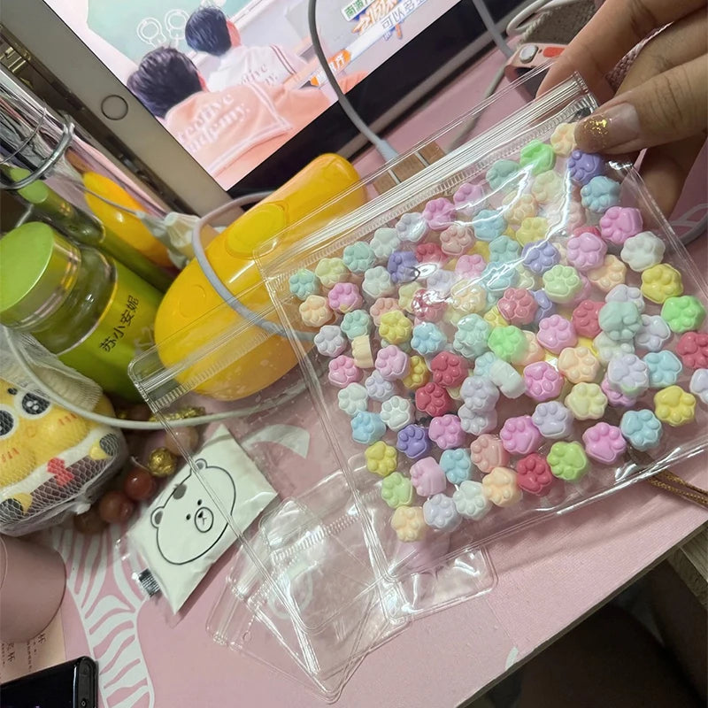 A clear plastic bag filled with numerous colorful cat paw squishy stress relief fidget toys