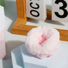 A pink, squishy stress relief ball rests on a white block next to wooden numbers.