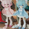 Two chibi-style vinyl art figures, one pink and one blue, are displayed next to some medical-themed items.