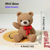 A dark brown Mini Bear plush toy standing on a card with text and an arrow.