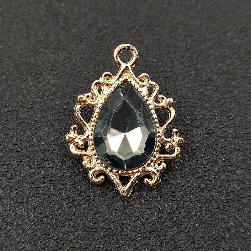 Gold plated water droplet charm featuring a faceted dark crystal gemstone set in an ornate flower design