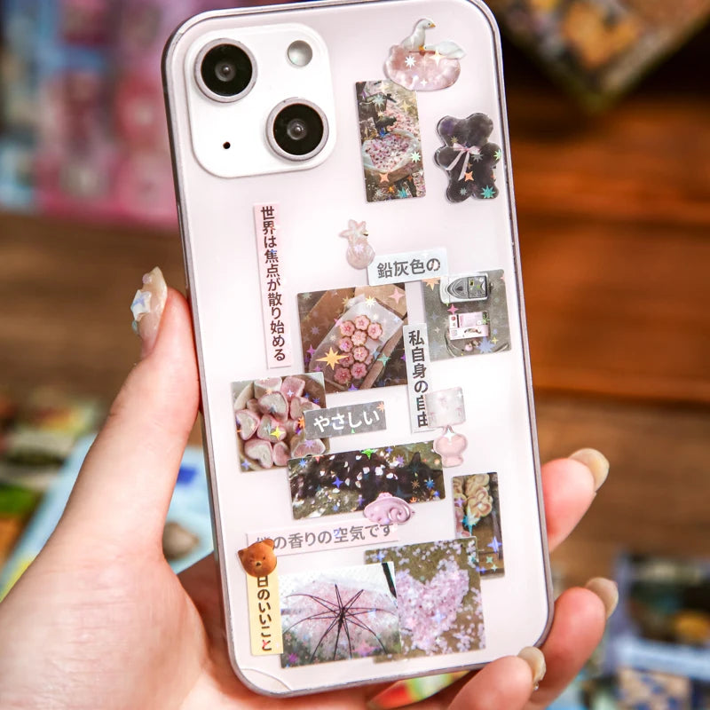 A hand holds a phone case featuring a Japanese vintage kawaii sticker pack for scrapbooking and journaling