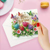 A greeting card featuring colorful butterfly and flower designs for a birthday, placed on pink paper.