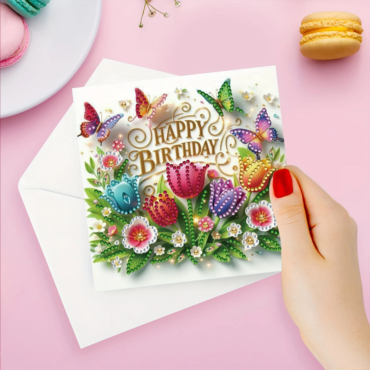 A greeting card featuring colorful butterfly and flower designs for a birthday, placed on pink paper.