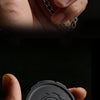 A hand holds a black metal roulette fidget spinner with a chain, showing the top view of the game roulette design.