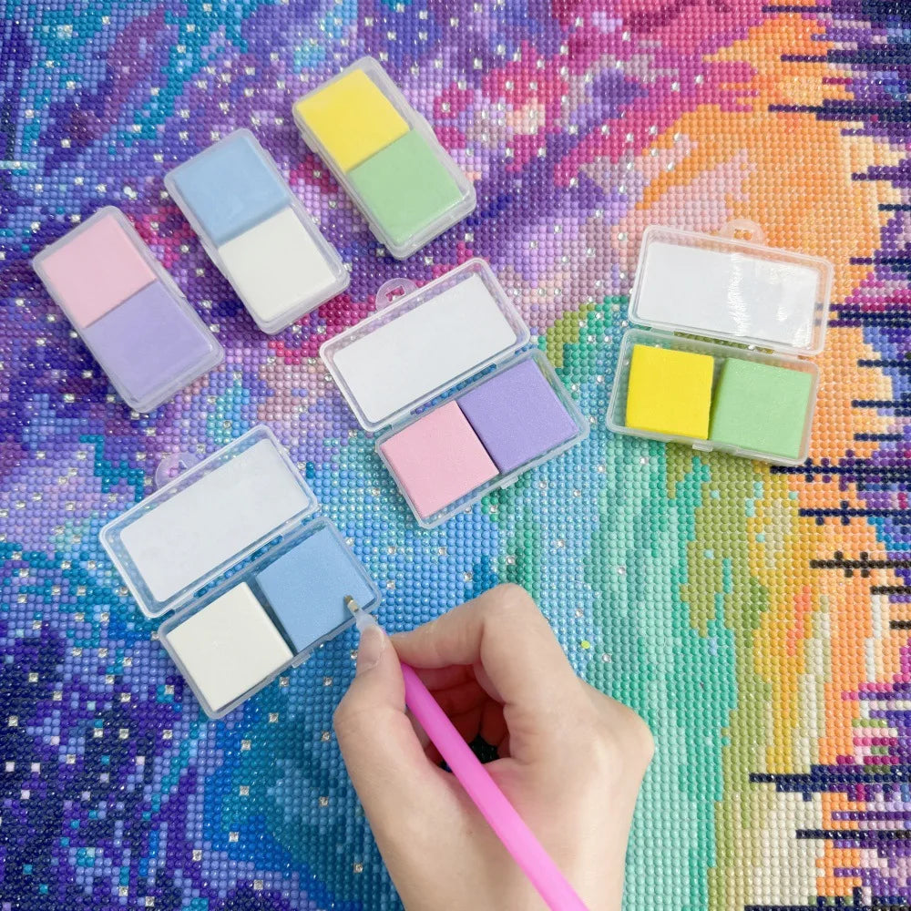 A collection of diamond painting putty wax in various pastel colors is arranged on a colorful, glittery surface.