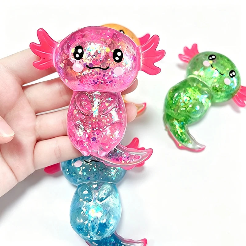 A hand holds a pink glitter axolotl squishy stress relief toy with bright green and blue variations.