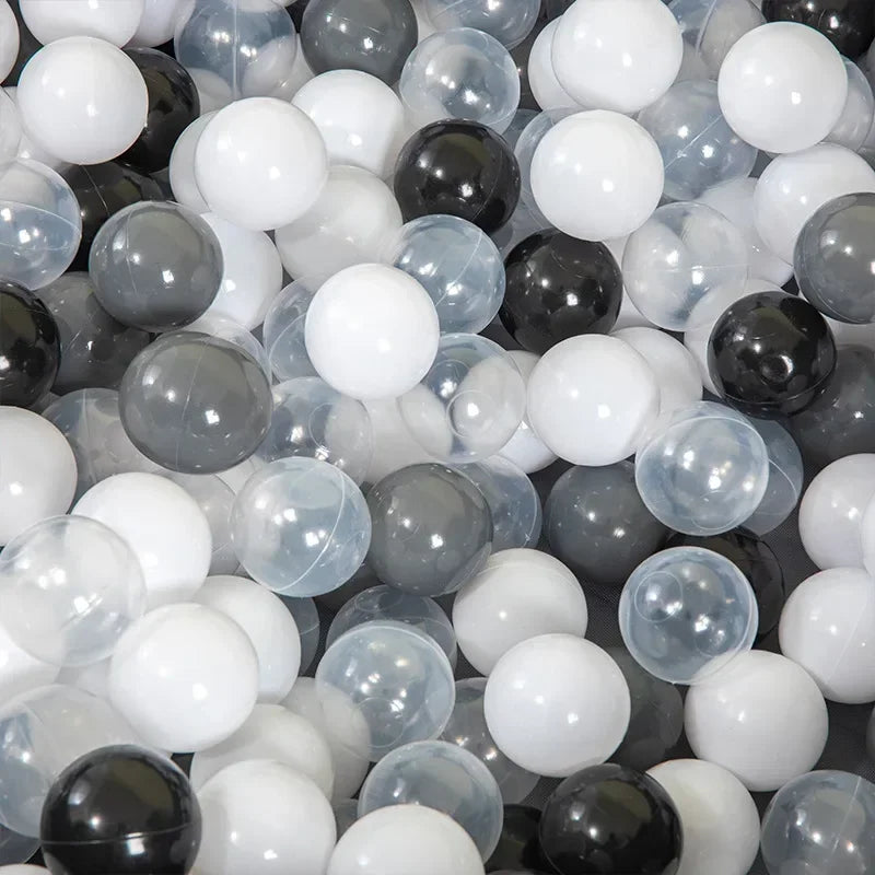 A close-up view of a bulk set of colorful plastic ocean ball pit toys in various shades of white, gray, and black.