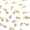 A scattered collection of gold-colored metal eye pins used for jewelry making and DIY crafts.
