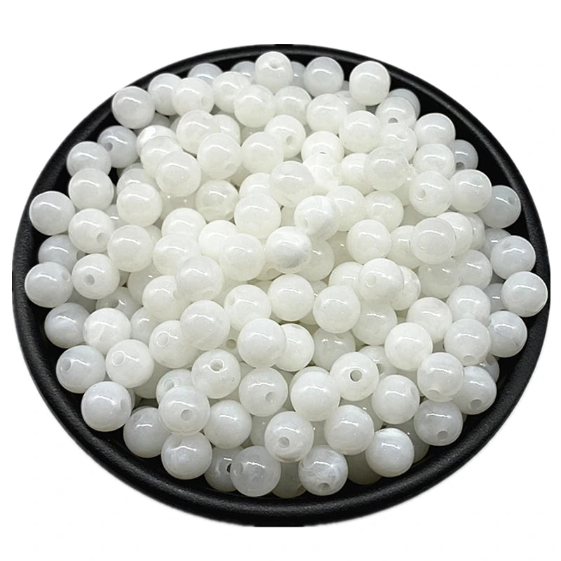 A pile of small, round, translucent white acrylic beads for jewelry making.