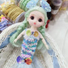 A mermaid doll with green hair adorned with blue flowers and a sequin dress