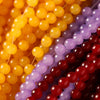 A close-up of various strands of colorful glass round beads in yellow, purple, and red.