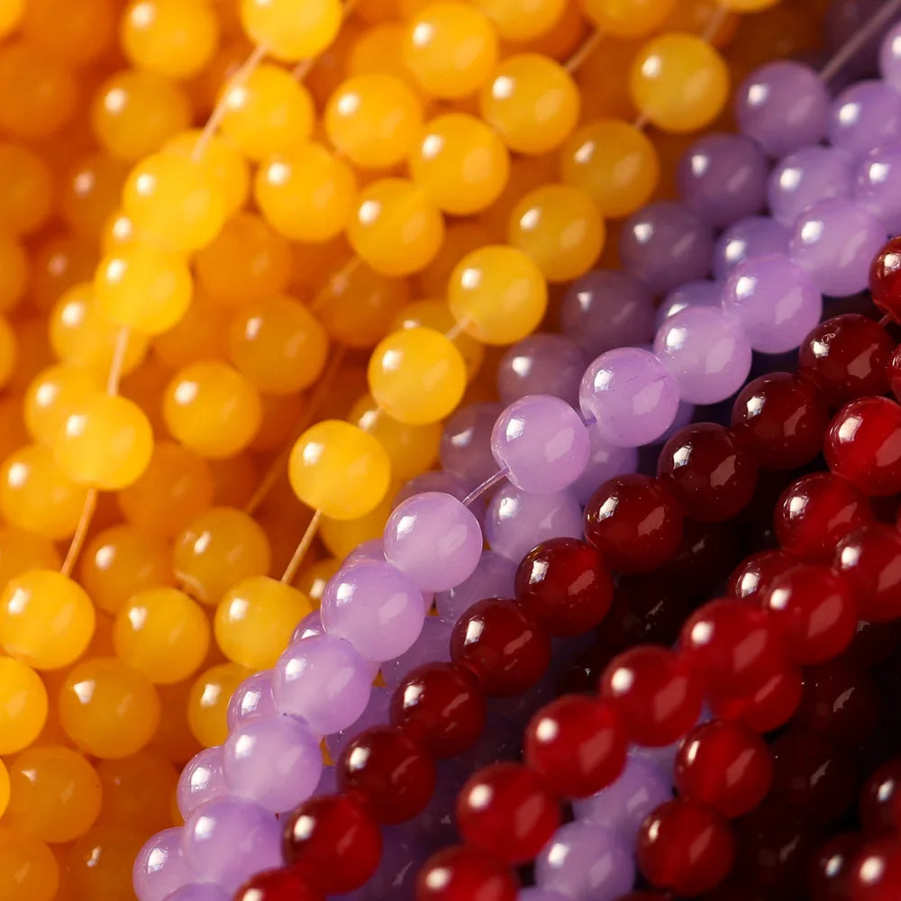A close-up of various strands of colorful glass round beads in yellow, purple, and red.